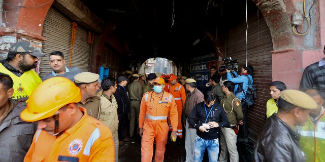 Medical officers and policemen walk near the site of a fire in an alleyway, tangled in electrical wire and too narrow for vehicles to access, in New Delhi, India, Sunday, Dec. 8, 2019. (Associated Press)