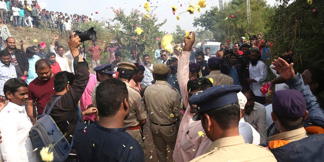 People throw flower petals on the Indian policemen guarding the area where rape accused were shot, in Shadnagar some 50 kilometers or 31 miles from Hyderabad, India, Friday, Dec. 6, 2019. An Indian police official says four men accused of raping and killing a woman in southern India have been fatally shot by police. (AP Photo/Mahesh Kumar A.)