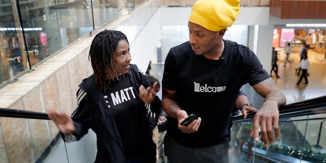 Miracle Washington-Tribble, left, and Houston Texans' De'Andre Hopkins, right, chat on an escalator as they shop for Christmas clothes Monday, Dec. 16, 2019, at Galleria Mall in Houston. Washington-Tribble and Jadon Cofield are beneficiaries of Eight Million Stories, a Houston program which helps 14-18-year-olds who have either quit or been kicked out of school continue their education, find employment and receive emotional support. (AP Photo/Michael Wyke)