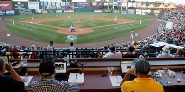 FILE - In this July 10, 2019, file photo, Ron Besaw, right, operates a laptop computer as home plate umpire Brian deBrauwere, gets signals from radar with the ball and strikes calls during the fourth inning of the Atlantic League All-Star minor league baseball game in York, Pa. (AP Photo/Julio Cortez, File)