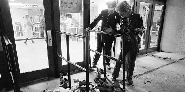 A security guard and an unidentified man look at an area where several people were killed as they were caught in a surging crowd entering Cincinnati's Riverfront Coliseum for a concert by the British rock band The Who, Dec. 3, 1979. (Associated Press)