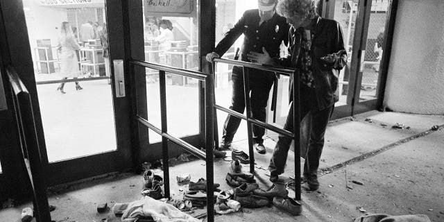 FILE - In this Dec. 3, 1979 file photo, a security guard and an unidentified man look at an area where several people were killed as they were caught in a surging crowd entering Cincinnati's riverfront coliseum for a concert by the British rock band The Who. (AP Photo/Brian Horton, File)