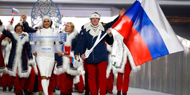 Alexander Zubkov of Russia carries the national flag as he leads the team during the opening ceremony of the 2014 Winter Olympics in Sochi, Russia. Model Irina Shayk, left, is seen carrying the Russian placard.