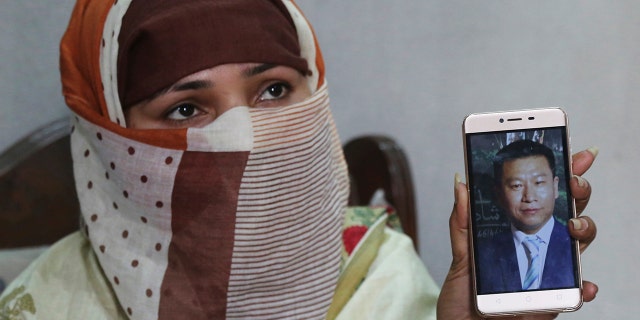 FILE - In this May 22, 2019 file photo, Sumaira a Pakistani woman, shows a picture of her Chinese husband in Gujranwala, Pakistan. Sumaira, who didn't want her full name used, was raped repeatedly by Chinese men at a house in Islamabad where she was brought to stay after her brothers arranged her marriage to the older Chinese man. (AP Photo/K.M. Chaudary, File)