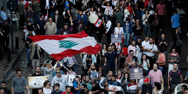Lebanese protesters wave their national flag, as they march in Beirut, Lebanon on Sunday. (AP Photo/Hussein Malla)