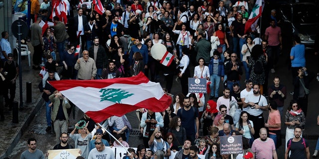 Lebanese protesters wave their national flag, as they march in Beirut, Lebanon on Sunday. (AP Photo/Hussein Malla)
