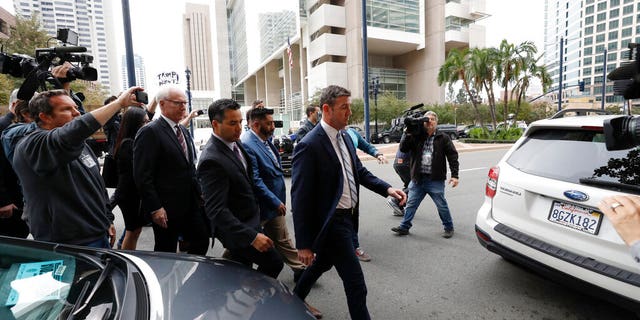 California Republican Rep. Duncan Hunter, center right, walks out of federal court Tuesday, Dec. 3, 2019, in San Diego. Hunter gave up his year-long fight against federal corruption charges and pleaded guilty Tuesday to misusing his campaign funds, paving the way for the six-term Republican to step down. (AP Photo/Gregory Bull)