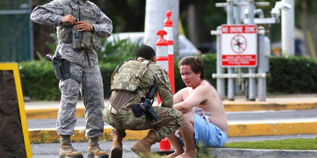 Security forces attend to an unidentified male outside the the main gate at Joint Base Pearl Harbor-Hickam, Wednesday, Dec. 4, 2019, in Hawaii, following a shooting. (AP Photo/Caleb Jones)