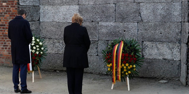 German Chancellor Angela Merkel, left, and Polish Prime Minister Mateusz Morawiecki, right, place flowers at the Death Wall during their visit of the former Nazi death camp of Auschwitz-Birkenau in Oswiecim, Poland.