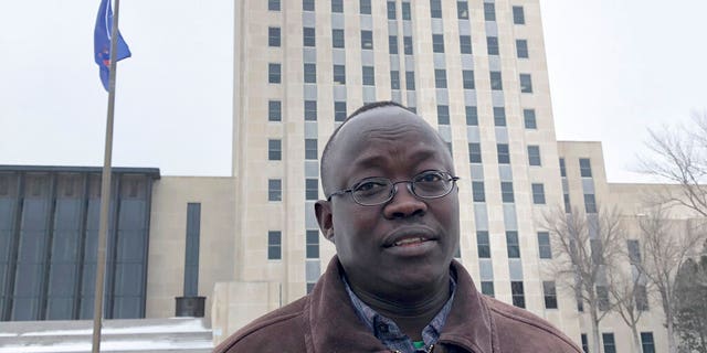 Reuben Panchol, who immigrated from Sudan to North Dakota as a child, standing in front of the North Dakota state capitol in Bismarck. 