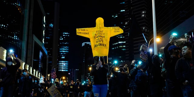 A protester holds up a rain coat with protests slogans during a rally in Hong Kong on Sunday, Dec. 8, 2019. Hundreds of thousands of demonstrators crammed into Hong Kong's streets on Sunday, their chants echoing off high-rises, in a mass show of support for a protest movement that shows no signs of flagging as it enters a seventh month. (AP Photo/Vincent Yu)