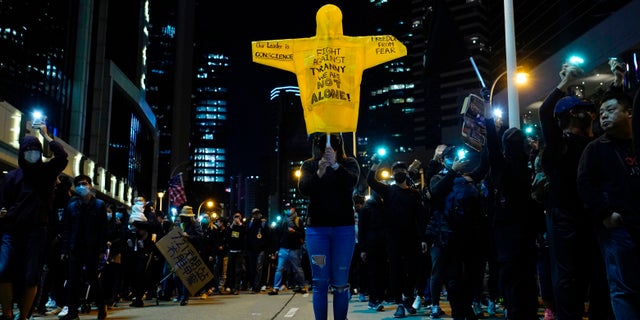 A protester holds up a rain coat with protests slogans during a rally in Hong Kong on Sunday, Dec. 8, 2019. Hundreds of thousands of demonstrators crammed into Hong Kong's streets on Sunday, their chants echoing off high-rises, in a mass show of support for a protest movement that shows no signs of flagging as it enters a seventh month. (AP Photo/Vincent Yu)