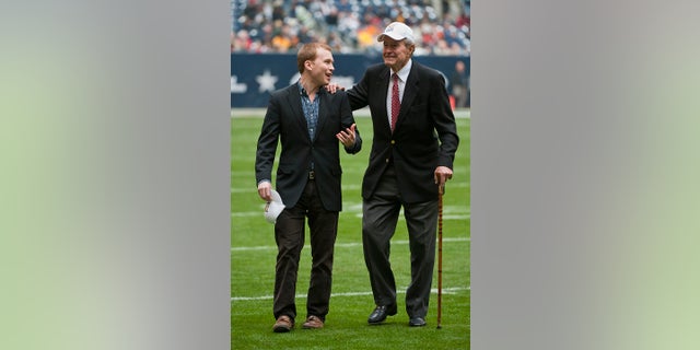 Former President George H. W. Bush leaving the field with the help of Pierce Bush, left, his grandson, before the a college football game in Houston, in 2009. (AP Photo/Dave Einsel, File)