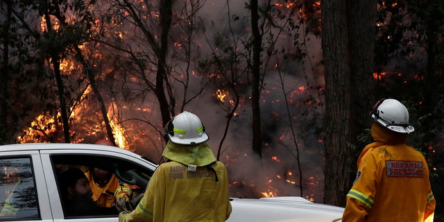 Firefighters talk with local residents as a fire burns near Mangrove Mountain, north of Sydney, Tuesday, Dec. 10, 2019. Hot dry conditions have brought an early start to the fire season. (AP Photo/Rick Rycroft)