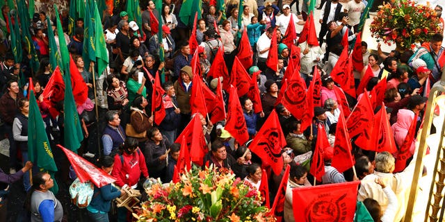 Farm workers block the entrance to the Fine Arts Palace to protest against a painting showing Emiliano Zapata straddling on a horse nude, wearing high heels and a pink, broad-brimmed hat, in Mexico City, Tuesday, Dec. 10, 2019. The work, by painter Fabian Chairez, is part of an exhibit remembering the one hundred anniversary of the revolutionary hero death. 