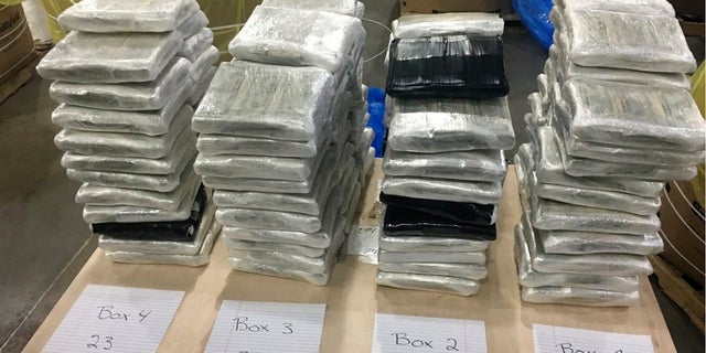 In this December 2019 photo provided by the Cleveland County Sheriff's Office in Shelby, N.C., approximately $3 million in cash, wrapped in plastic, is displayed near the barrels of raw pork shoulder in which it was discovered in. North Carolina deputies recovered the barrels on Dec. 7 from a tractor-trailer they pulled over. (Cleveland County Sheriff's Office via AP)