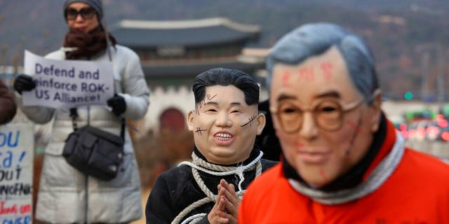 Protesters wear masks of North Korean leader Kim Jong Un and South Korean President Moon Jae-in, right, during a rally to denounce policies of Moon on North Korea near the U.S. embassy in Seoul, South Korea, Friday, Dec. 13, 2019.