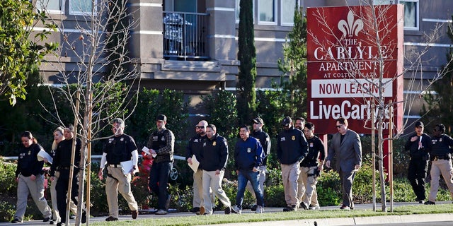 Federal agents entering an upscale apartment complex where investigators said a birth tourism business charged pregnant women $50,000 for lodging, food and transportation, in Irvine, Calif., in 2015. (AP Photo/Jae C. Hong, File)