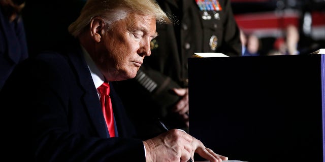President Donald Trump signs the National Defense Authorization Act for Fiscal Year 2020 at Andrews Air Force Base, Md., Friday, Dec. 20, 2019. (AP Photo/Andrew Harnik)