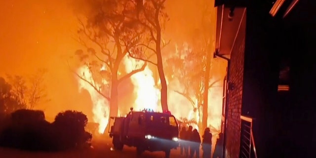 This image made from video taken on Dec. 22, 2019, and provided Dec. 25, 2019, by Ingleside Rural Fire Brigade, shows the wildfire behind an emergency vehicle near property on Hat Hill Road in Blackheath, New South Wales. Australian authorities have warned that the fires in New South Wales could fester for months, causing more angst for exhausted firefighters.(Ingleside Rural Fire Brigade via AP)