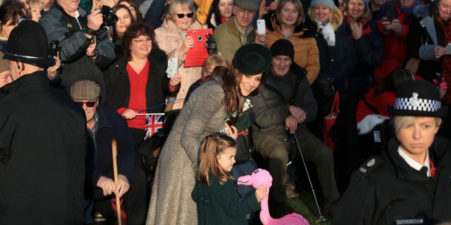 Britain's Catherine, Duchess of Cambridge, center left, speaks with her daughter Princess Charlotte as she holds a pink flamingo while greeting the public outside the St Mary Magdalene Church in Sandringham in Norfolk, England, Wednesday, Dec. 25, 2019. (AP Photo/Jon Super)