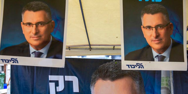 A Likud party member sits by a poster of veteran politician Gideon Saar from the governing Likud Party at a voting center in the northern Israeli city of Hadera, Thursday, Dec. 26, 2019. 