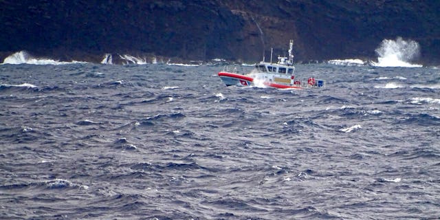 In this photo released by the U.S. Coast Guard, a coast guard vessel searches along the Na Pali Coast on the Hawaiian island of Kauai on Friday, Dec. 27, 2019, the day after a tour helicopter disappeared with seven people aboard. Authorities say wreckage of the helicopter has been found in a mountainous area on the island.
