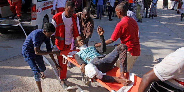 Medical personnel carry a civilian who was wounded in suicide car bomb attack at check point in Mogadishu, Somalia, Saturday, Dec, 28, 2019. (Associated Press)