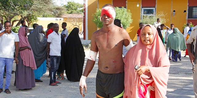 A civilian who was wounded in suicide car bomb attack is helped at check point in Mogadishu, Somalia, Saturday, Dec, 28, 2019. (Associated Press)
