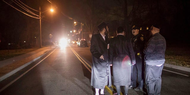 Orthodox Jewish residents talk with police on Forshay Road in Monsey, N.Y., Sunday, Dec. 29, 2019, down the street from the scene of a stabbing that occurred late Saturday during a Hanukkah celebration. A man attacked at a rabbi's home north of New York City late Saturday, stabbing and wounding several people before fleeing in a vehicle, police said. (Associated Press)