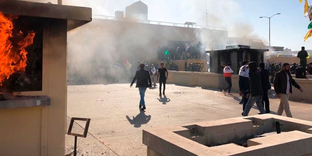 Dozens of Iraqi Shiite militia supporters are seen at the U.S. embassy compound where a fire was set to a reception area, in Baghdad, Iraq, Tuesday, Dec. 31, 2019. (AP Photo/Qassim Abdul-Zahra)