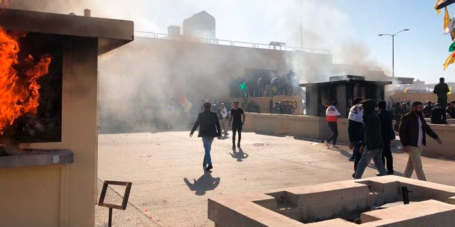 Dozens of Iraqi Shiite militia supporters are seen at the U.S. embassy compound where a fire was set to a reception area, in Baghdad, Iraq, Tuesday, Dec. 31, 2019. (AP Photo/Qassim Abdul-Zahra)