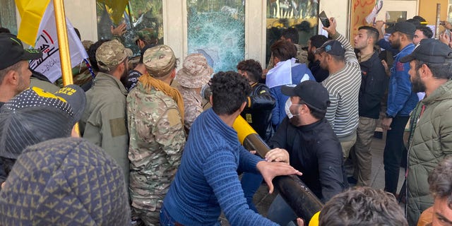 Protesters smashing a window inside the U.S. embassy compound Tuesday. (AP Photo/Khalid Mohammed)