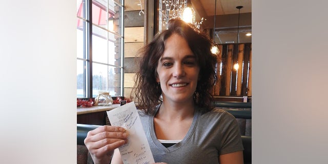 Server Danielle Franzoni holds a receipt from a customer with a $2,020 tip at the Thunder Bay River Restaurant in Alpena, Mich. The credit card receipt said "Happy New Year. 2020 Tip Challenge." (Julie Riddle/The News via AP)