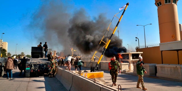 Security forces standing guard while protesters burned property in front of the U.S. Embassy compound in Baghdad on Tuesday. (AP Photo/Khalid Mohammed)