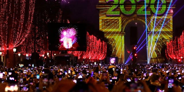 Revellers photograph fireworks over the Arc de Triomphe as they celebrate the New Year on the Champs Elysees, in Paris, France, Wednesday, Jan. 1, 2020. (Associated Press)