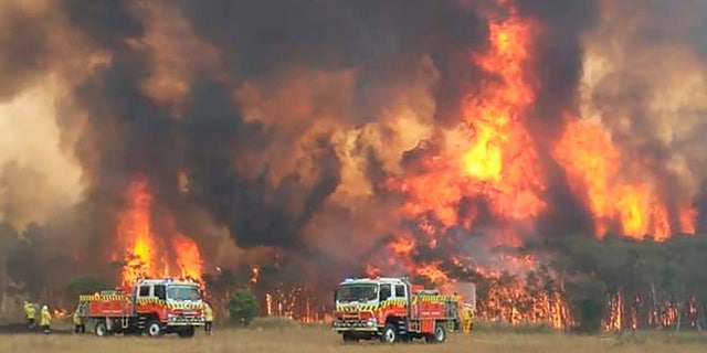 In this image dated Dec. 30, 2019, and provided by NSW Rural Fire Service via their twitter account, firefighters are seen as they try to protect homes around Charmhaven, New South Wales.
