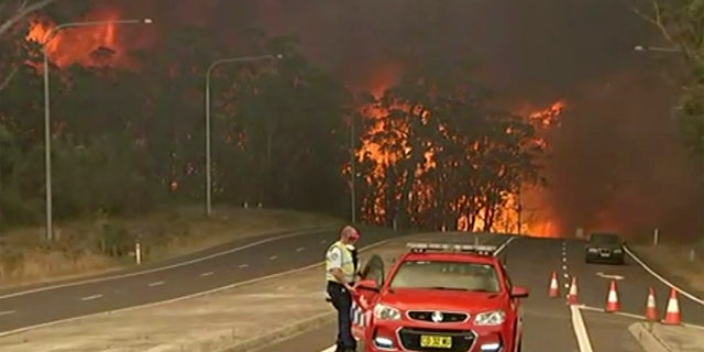 In this image made from video, officials block the Princes Highway as wildfires approach in South Coast, New South Wales Australia, Tuesday, Dec. 31, 2019.