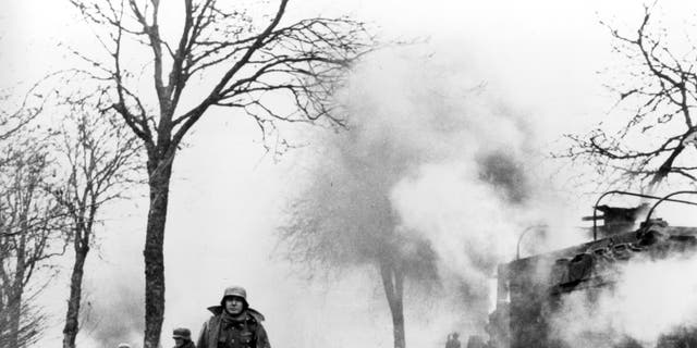 In this Dec. 1944 file photo, German infantrymen pass by burning captured American vehicles during the drive into Allied lines on the Western Front during the Battle of the Bulge.