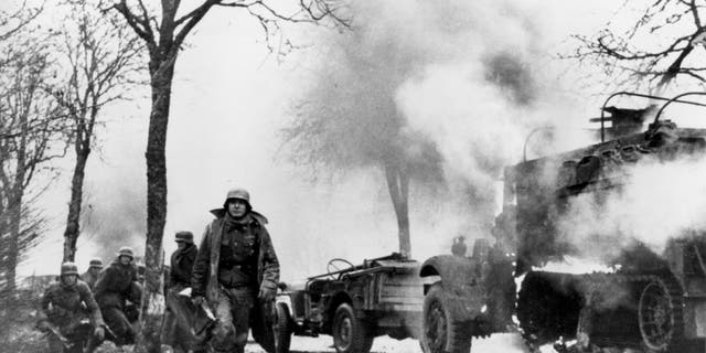 In this Dec. 1944 file photo, German infantrymen pass by burning captured American vehicles during the drive into Allied lines on the Western Front during the Battle of the Bulge.