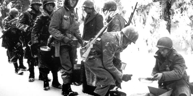 FILE - In this Jan. 13, 1945 file photo, and provided by the U.S. Army, American soldiers of the 347th U.S. Infantry wear heavy winter gear as they receive rations in La Roche, Belgium.