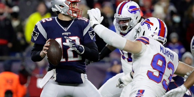 In this Dec. 21, 2019 file photo, New England Patriots quarterback Tom Brady, left, passes under pressure from Buffalo Bills defensive end Trent Murphy (93) during the first half of a game in Foxborough, Massachusetts. 