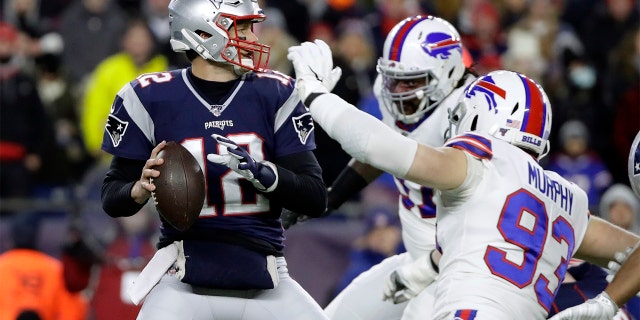 In this Dec. 21, 2019 file photo, New England Patriots quarterback Tom Brady, left, passes under pressure from Buffalo Bills defensive end Trent Murphy (93) during the first half of a game in Foxborough, Massachusetts. 