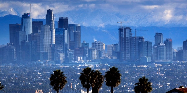 Heavy storm clouds and a dusting of snow are seen in the San Gabriel mountain range behind downtown Los Angeles.