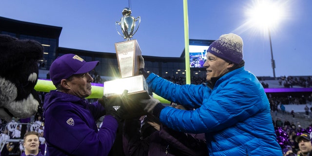 Washington Governor Jay Inslee hands Washington head coach Chris Petersen the Apple Cup after an NCAA college football game between Washington and Washington State, on Friday, Nov. 29, 2019 in Seattle. Washington won 31-13. (AP Photo/Stephen Brashear)
