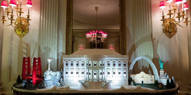 A White House made of gingerbread surrounded by landmarks from around the country in the State Dining Room during the 2019 Christmas preview. [AP Photo/Alex Brandon)