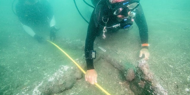 Marine archaeologists measure one of the 16th-century anchors.