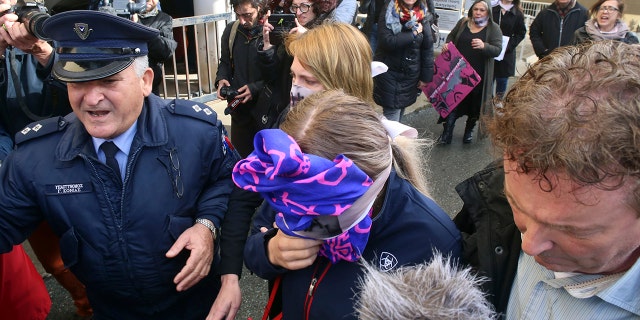 A 19-year-old British woman, center, covers her face as she leaves from the Famagusta court after her trial, in Paralimni, Cyprus, on Monday.