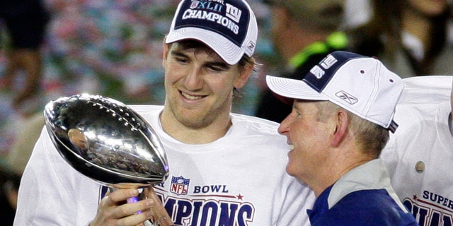 Esta foto de archivo del 3 de febrero de 2008 muestra al mariscal de campo de los New York Giants, Eli Manning, a la izquierda, y a su entrenador Tom Coughlin mirando el trofeo Vince Lombardi mientras celebran después de que los Giants derrotaron a los Patriots de Nueva Inglaterra 17-14 en el Super Bowl XLII en Glendale. .  , Arizona 