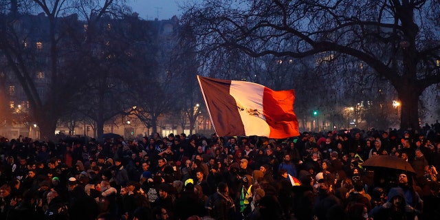 A person waves a French tricolor at the end of a demonstration Tuesday, Dec.17, 2019, in Paris. People from across the French workforce walked off the job Tuesday to resist a higher retirement age and to preserve a welfare system they fear their business-friendly president wants to dismantle. (AP Photo/Francois Mori)